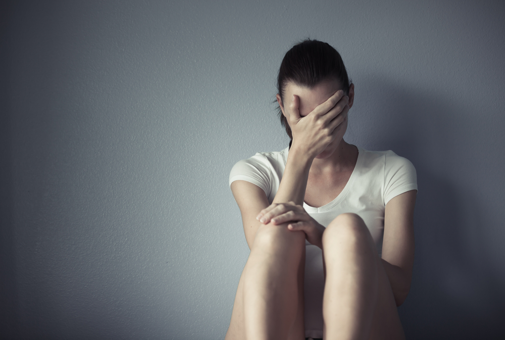 Sad woman sitting against a wall