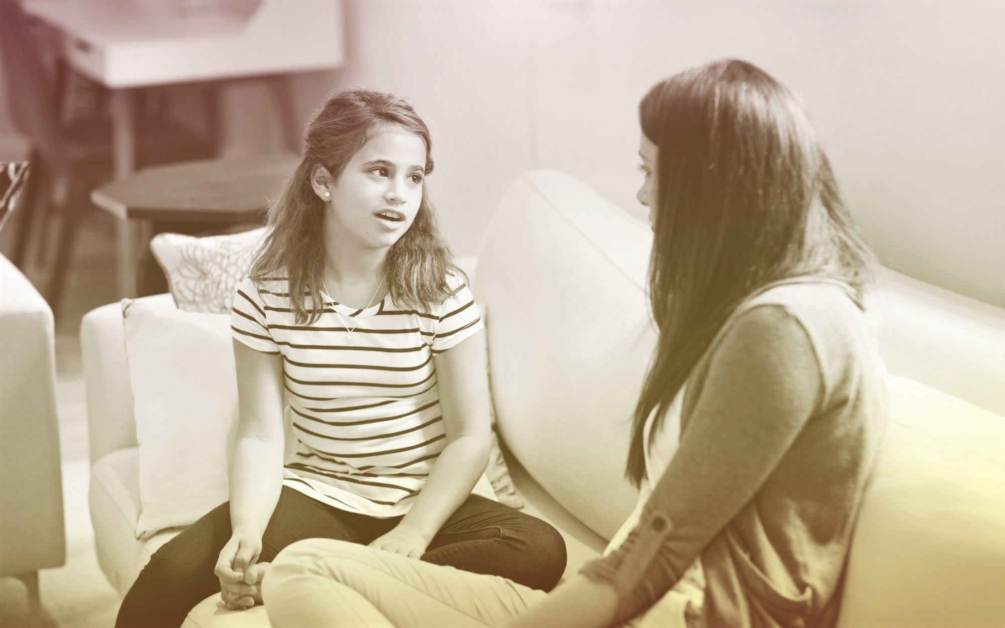 daughter talking to mother on sofa at home