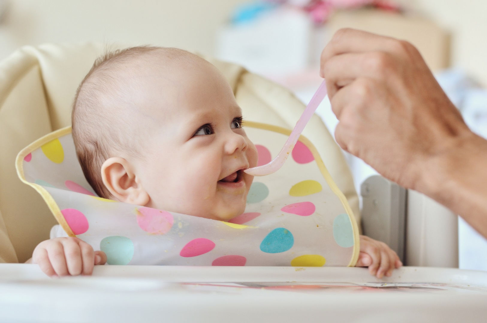 Baby Eating From Spoon Sitting in Highchair