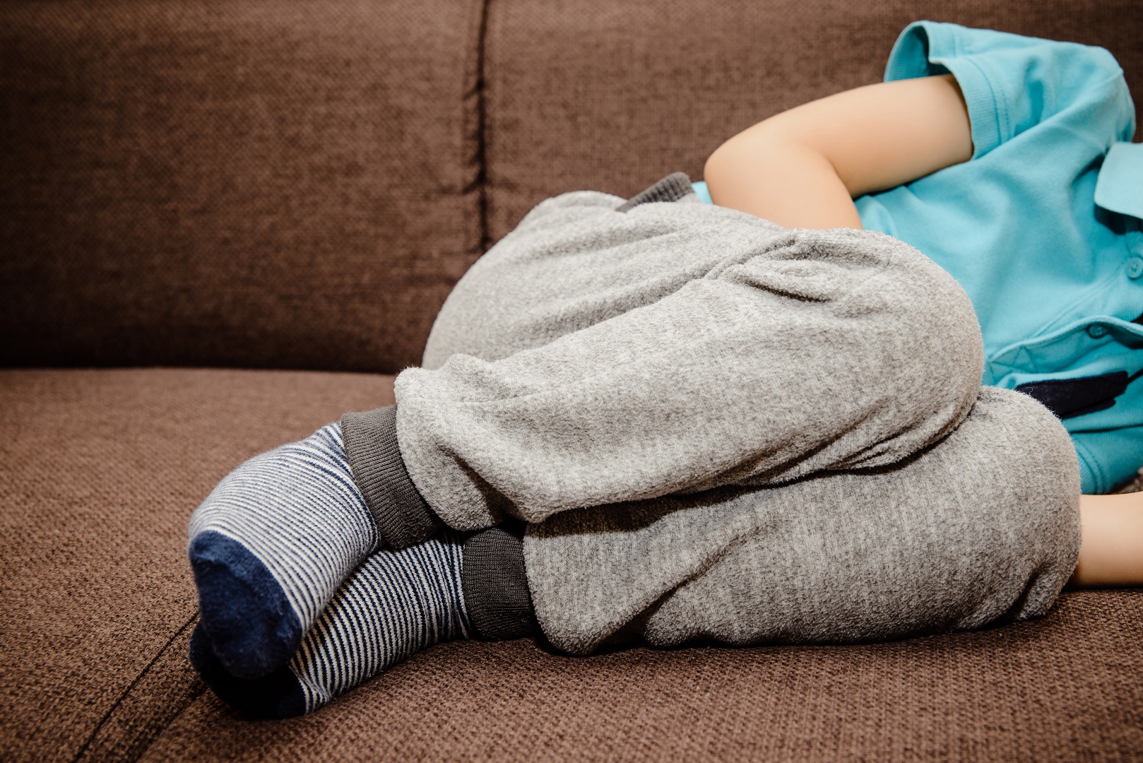 Young Boy Laying Down Holding Belly Stomach Ache