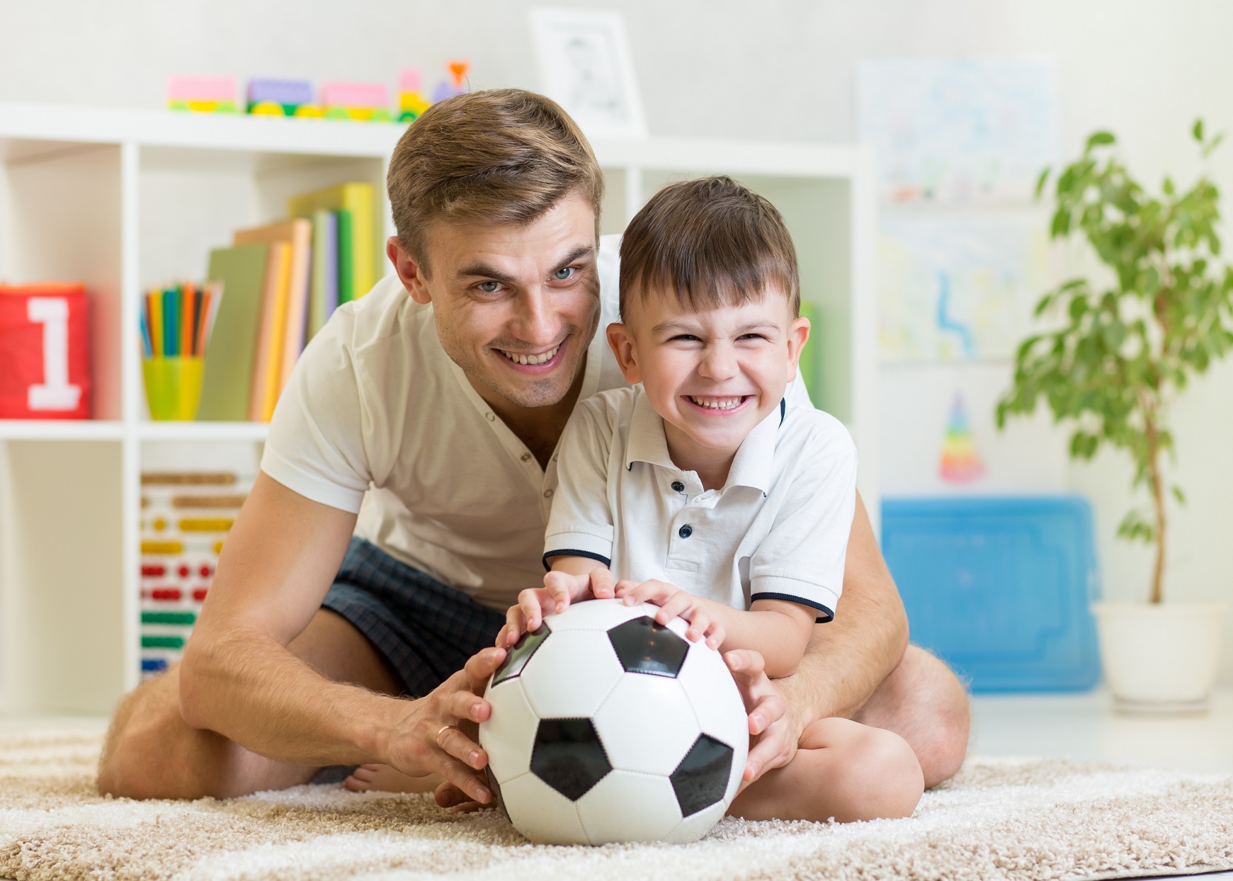 dad and son playing soccer indoors 34975