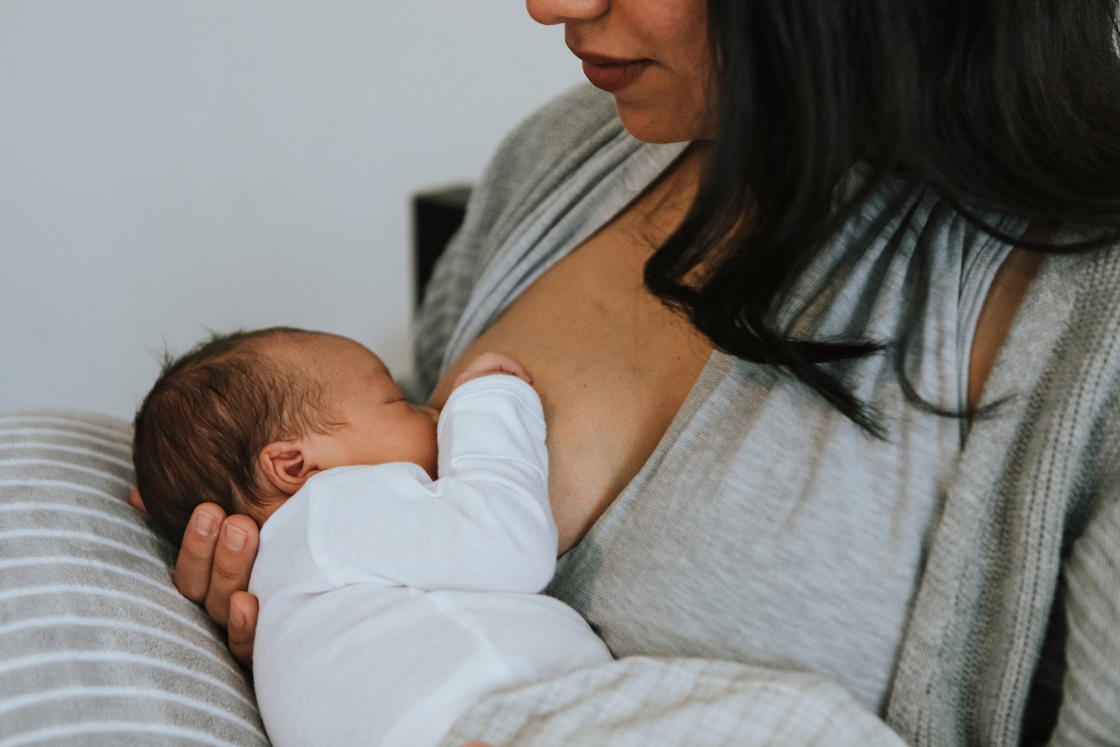 Dark Hair Woman Breastfeeding Baby Gray Shirt